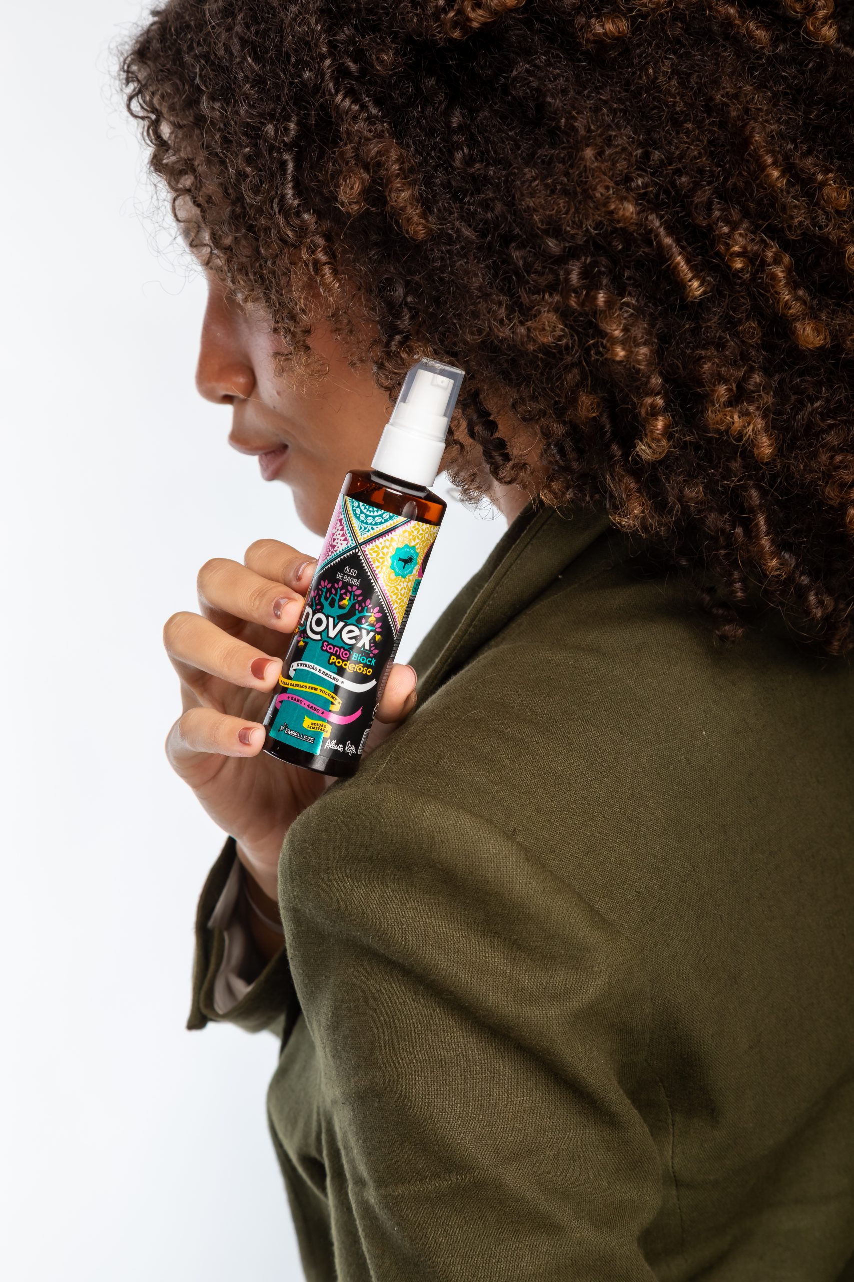 Mulher segurando spray para cabelo com franja cacheada